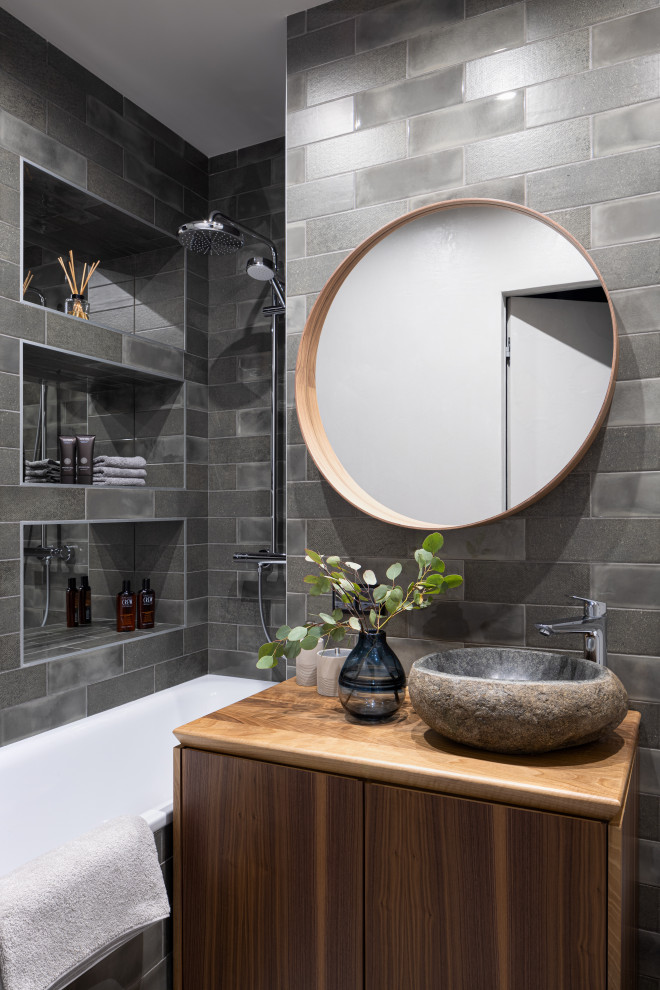 Свежая идея для дизайна: главная ванная комната в современном стиле с плоскими фасадами, фасадами цвета дерева среднего тона, серой плиткой, настольной раковиной и коричневой столешницей - отличное фото интерьера