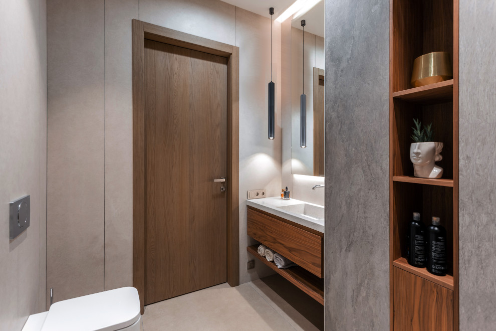 Diseño de cuarto de baño único y flotante actual con armarios con paneles lisos, puertas de armario de madera oscura, sanitario de pared, paredes grises, lavabo integrado, suelo gris y encimeras blancas