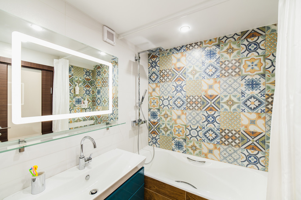 Inspiration pour une salle de bain principale design avec un placard à porte plane, des portes de placard bleues, une baignoire en alcôve, un combiné douche/baignoire, un carrelage multicolore, un mur blanc, un lavabo intégré et une cabine de douche avec un rideau.