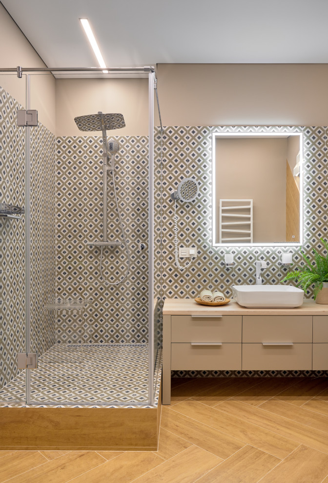 На фото: ванная комната в современном стиле с плоскими фасадами, бежевыми фасадами, угловым душем, разноцветной плиткой, коричневыми стенами, настольной раковиной, коричневым полом, душем с распашными дверями, бежевой столешницей и зеркалом с подсветкой с