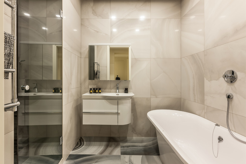 Пример оригинального дизайна: главная ванная комната в современном стиле с плоскими фасадами, белыми фасадами, отдельно стоящей ванной, душем в нише, серой плиткой и монолитной раковиной