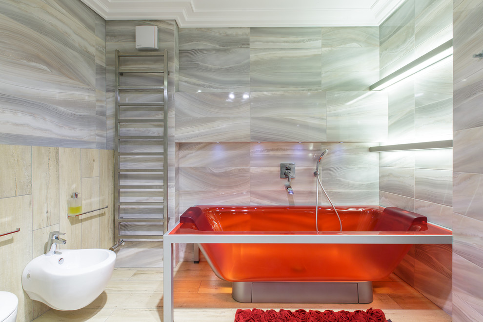 Стильный дизайн: ванная комната среднего размера в современном стиле с отдельно стоящей ванной, биде, светлым паркетным полом и серой плиткой - последний тренд