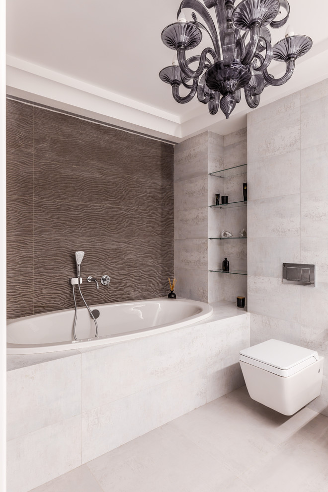 Ejemplo de cuarto de baño principal contemporáneo con bañera encastrada, sanitario de pared, baldosas y/o azulejos marrones y suelo gris