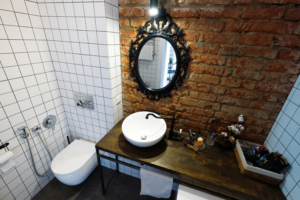 This is an example of a medium sized eclectic ensuite bathroom in Other with a wall mounted toilet, white tiles, ceramic tiles, ceramic flooring, a vessel sink, wooden worktops and grey floors.
