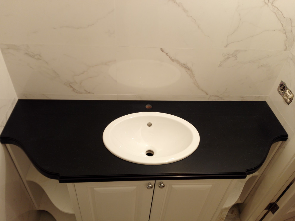 Inredning av ett klassiskt litet svart svart badrum, med beige kakel, ett nedsänkt handfat och bänkskiva i akrylsten