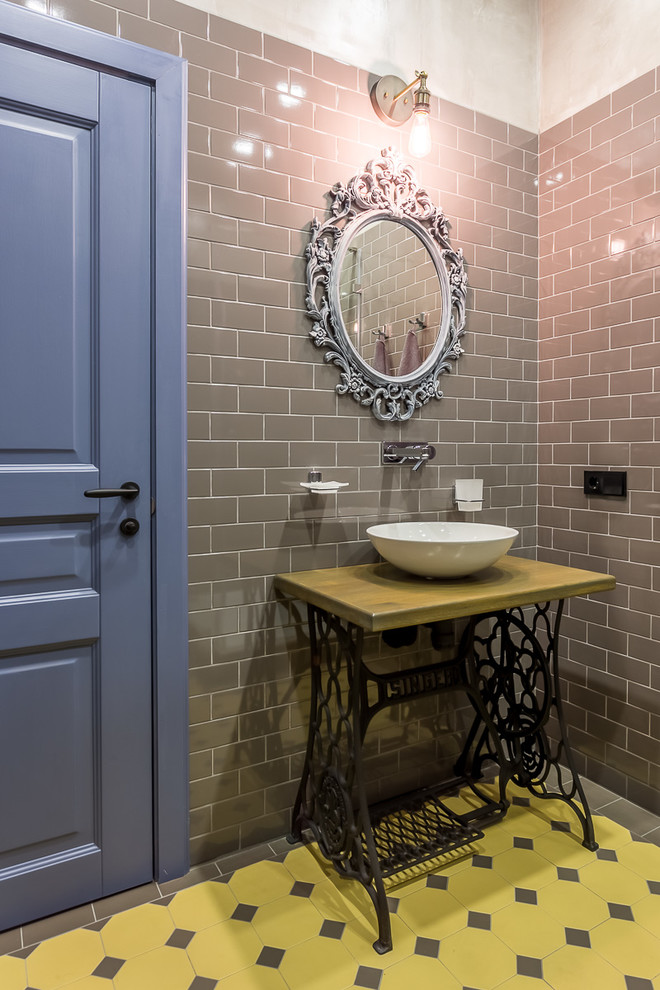 Industrial bathroom in Moscow with yellow tiles, grey tiles, grey walls and a vessel sink.