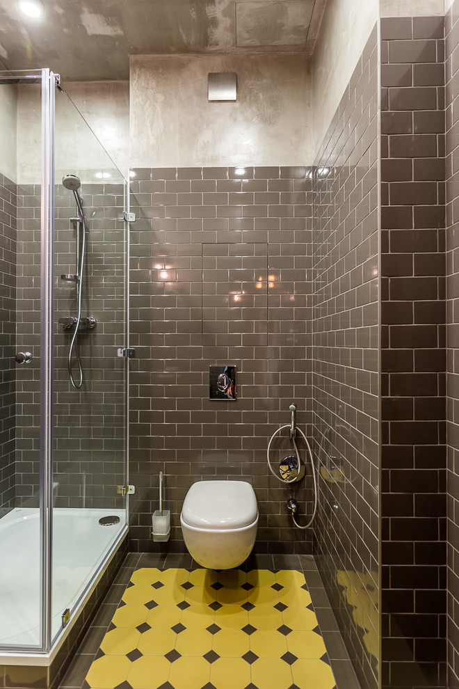 Réalisation d'une salle d'eau urbaine avec une douche d'angle, WC suspendus, un carrelage jaune, un carrelage gris et un mur gris.