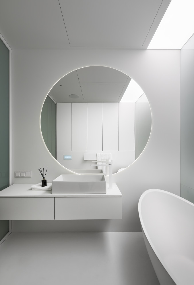 Réalisation d'une salle d'eau design de taille moyenne avec un placard à porte plane, des portes de placard blanches, une baignoire indépendante, un mur blanc, une vasque, un sol blanc, un plan de toilette blanc, meuble simple vasque et meuble-lavabo suspendu.