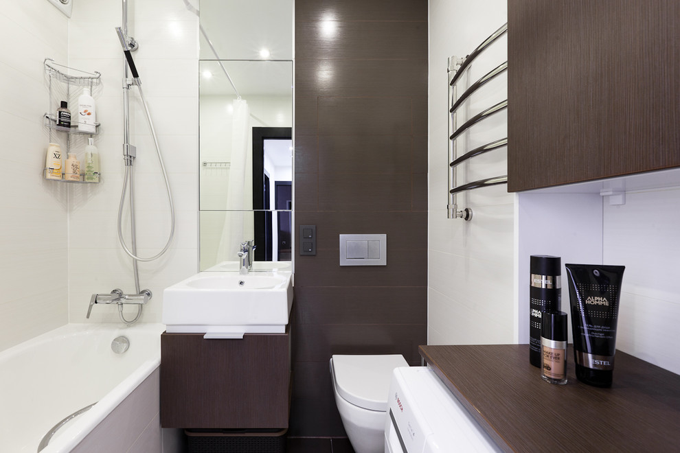 Cette photo montre une petite salle de bain principale tendance en bois foncé avec un placard à porte plane, des carreaux de porcelaine, un sol en carrelage de porcelaine, une baignoire en alcôve et un lavabo intégré.