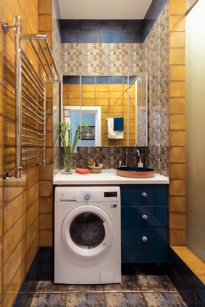 Стильный дизайн: ванная комната среднего размера со стиральной машиной в стиле фьюжн с плоскими фасадами, синими фасадами, душем в нише, оранжевой плиткой, керамической плиткой, полом из керамической плитки, душевой кабиной, накладной раковиной, столешницей из искусственного камня и разноцветным полом - последний тренд