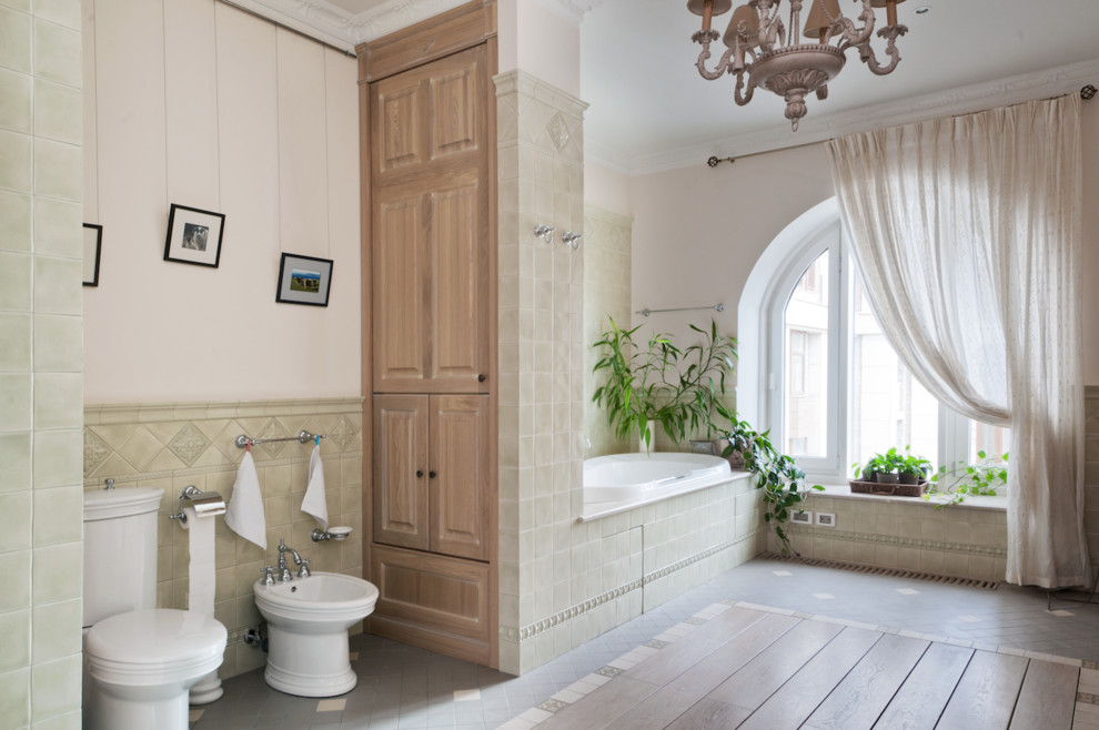 Foto di una stanza da bagno padronale tradizionale con ante con bugna sagomata, ante in legno chiaro, vasca da incasso, WC a due pezzi, piastrelle grigie e pareti bianche