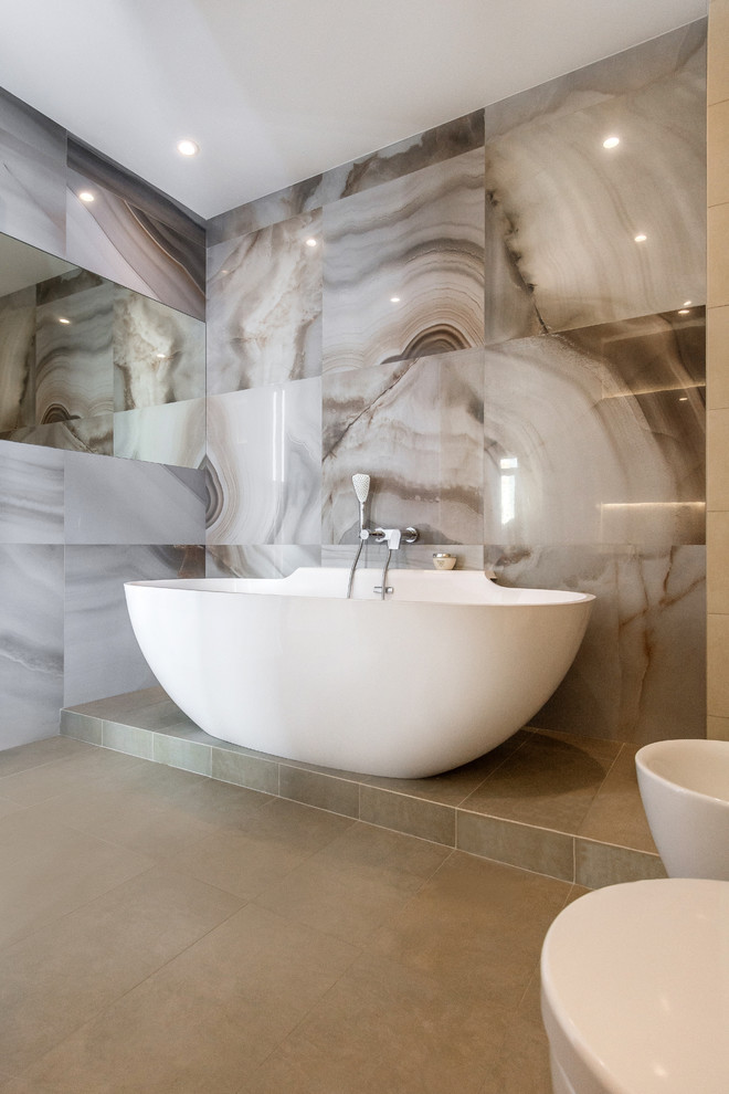 На фото: главная ванная комната в современном стиле с отдельно стоящей ванной и бежевым полом