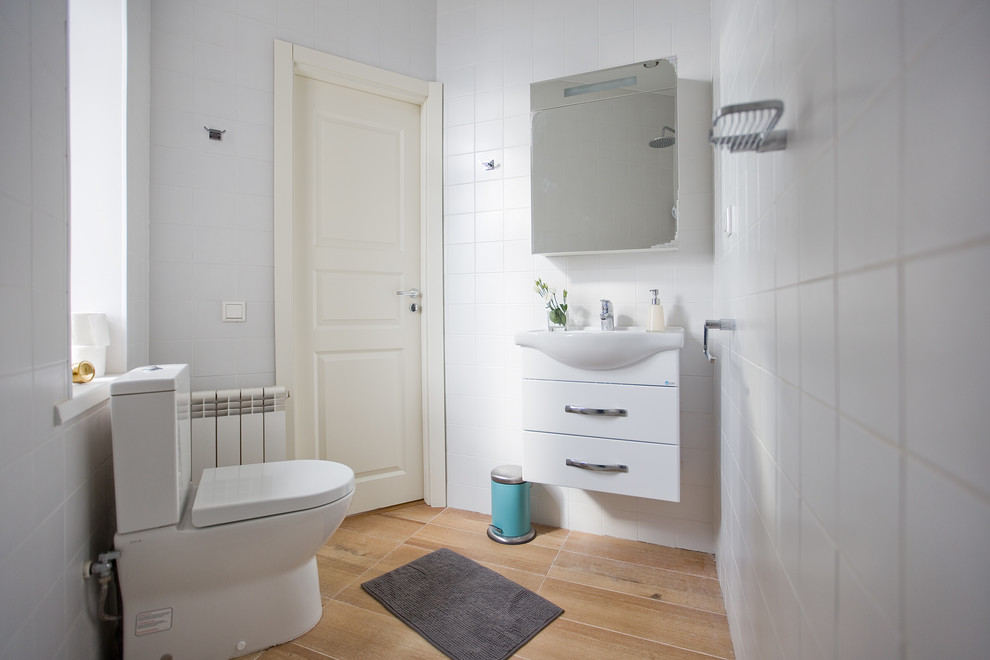 На фото: маленькая ванная комната в современном стиле с угловым душем, унитазом-моноблоком, белой плиткой, керамической плиткой, белыми стенами, полом из ламината, врезной раковиной, желтым полом и открытым душем для на участке и в саду