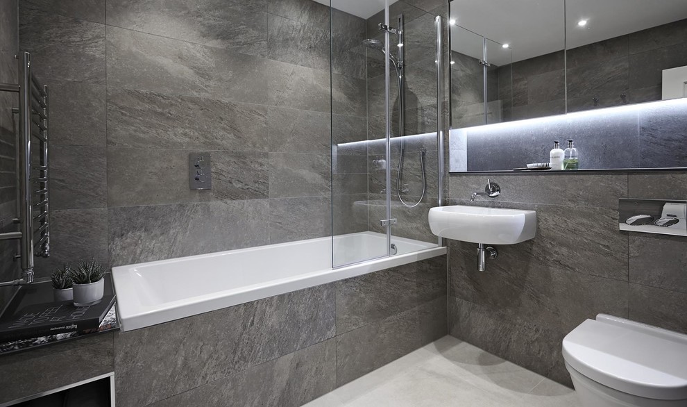 Imagen de cuarto de baño principal y gris y blanco contemporáneo de tamaño medio con bañera empotrada, sanitario de pared, baldosas y/o azulejos de travertino, suelo de mármol, lavabo suspendido, encimera de cuarzo compacto y suelo blanco