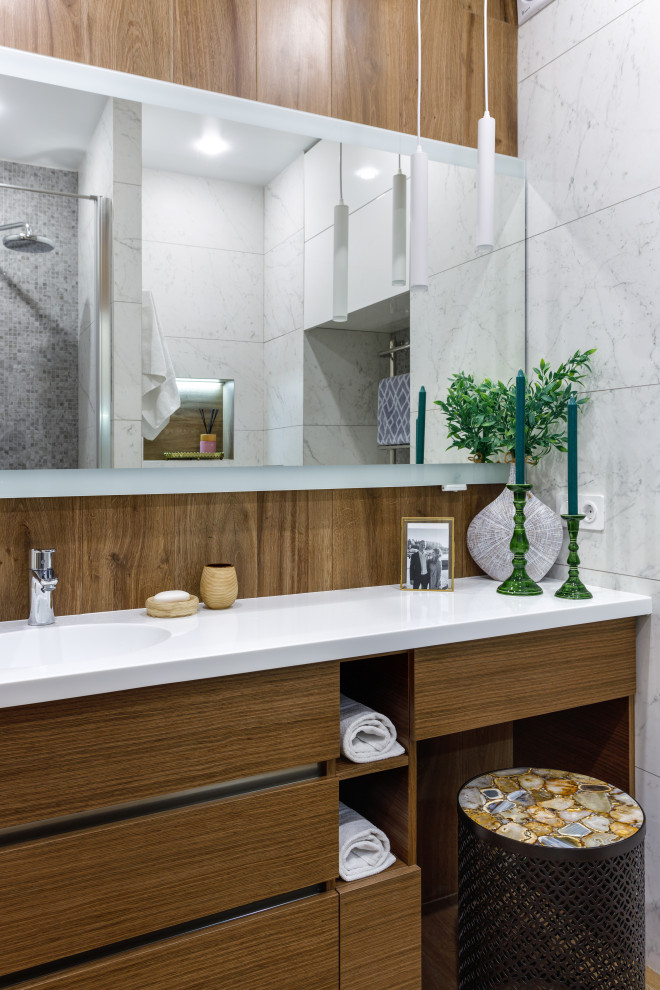 Diseño de cuarto de baño blanco y madera actual con armarios con paneles lisos, puertas de armario de madera oscura, baldosas y/o azulejos blancos, lavabo integrado y encimeras blancas
