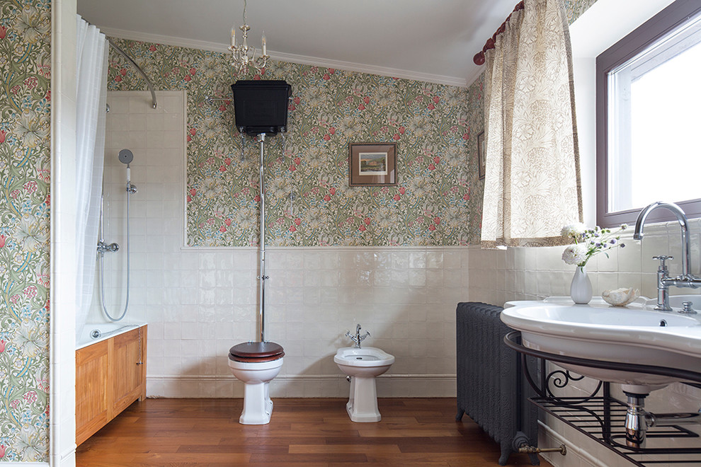 Modelo de cuarto de baño principal clásico con armarios abiertos, bañera empotrada, bidé, baldosas y/o azulejos blancos, paredes multicolor, lavabo suspendido y suelo de madera en tonos medios