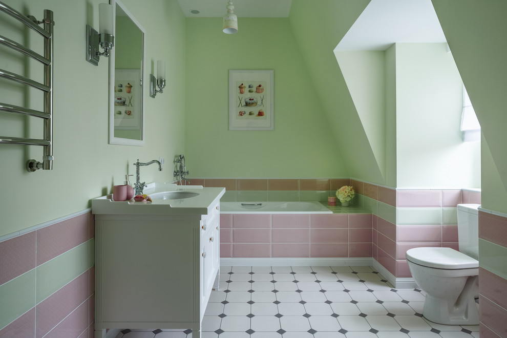 На фото: детская ванная комната среднего размера в стиле неоклассика (современная классика) с белыми фасадами, раздельным унитазом, зеленой плиткой, розовой плиткой, каменной плиткой, полом из керамической плитки, столешницей из искусственного камня, разноцветным полом, накладной ванной, зелеными стенами и врезной раковиной с