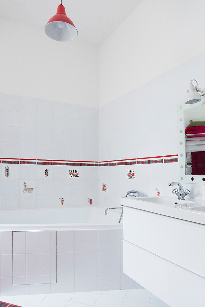 Cette photo montre une salle de bain tendance pour enfant avec un placard à porte plane, des portes de placard blanches, une baignoire d'angle, un combiné douche/baignoire, un carrelage blanc, un mur blanc et un lavabo posé.