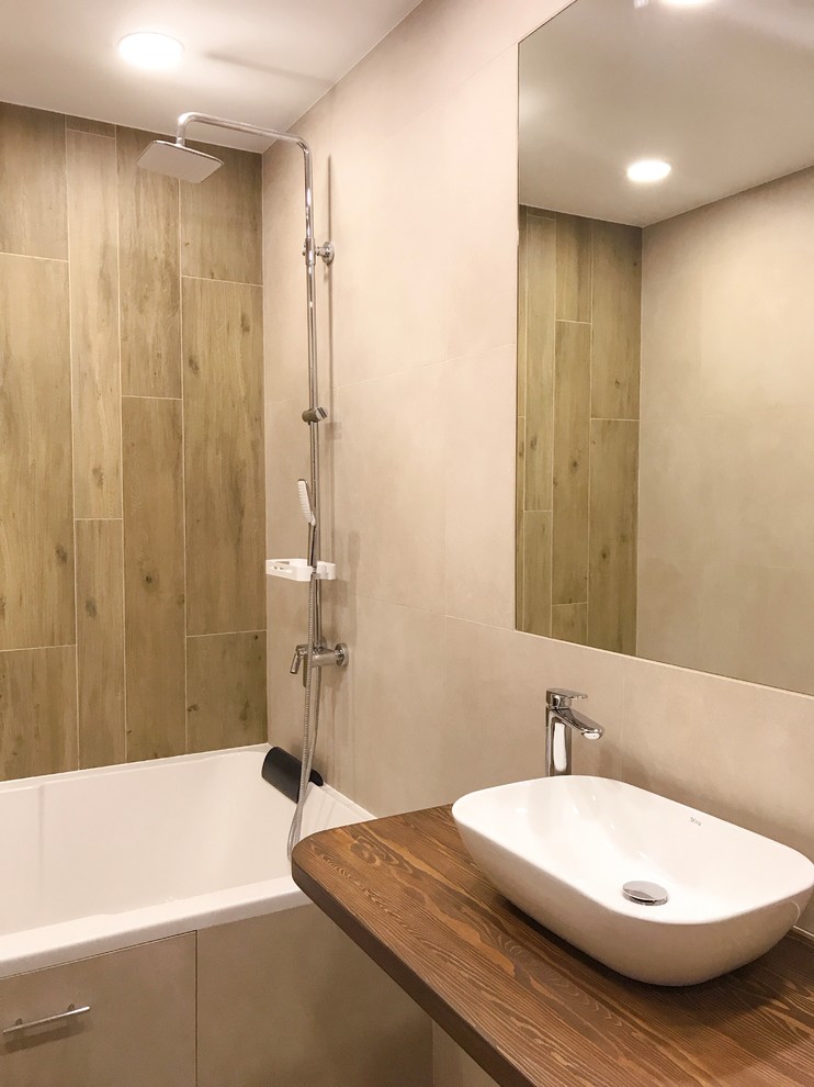 Idéer för mellanstora funkis brunt en-suite badrum, med ett badkar med tassar, beige kakel, porslinskakel, beige väggar, klinkergolv i porslin, ett nedsänkt handfat, träbänkskiva och brunt golv