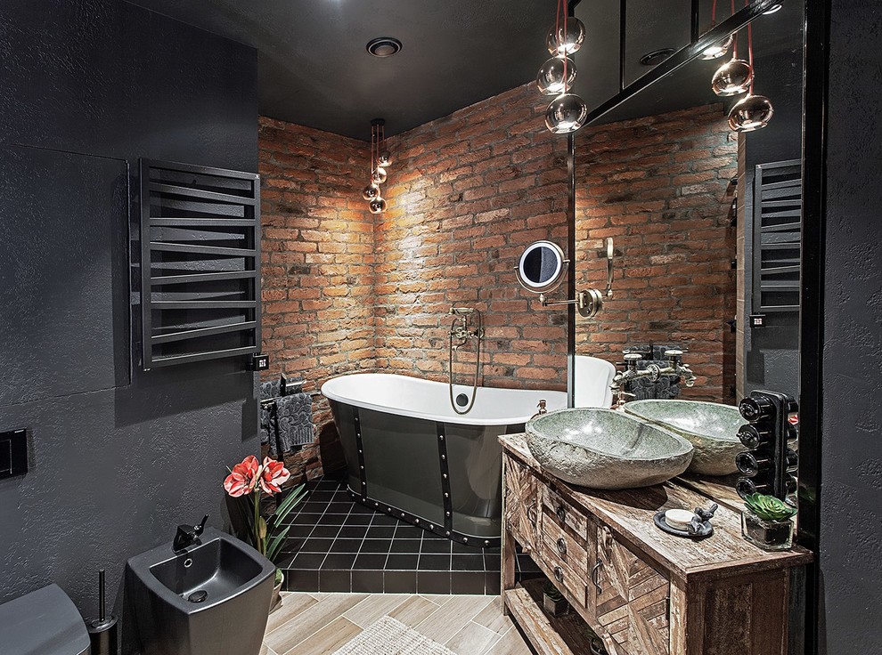 Идея дизайна: главная ванная комната в стиле лофт с плоскими фасадами, искусственно-состаренными фасадами, отдельно стоящей ванной, черной плиткой, черными стенами, настольной раковиной, столешницей из дерева и коричневой столешницей