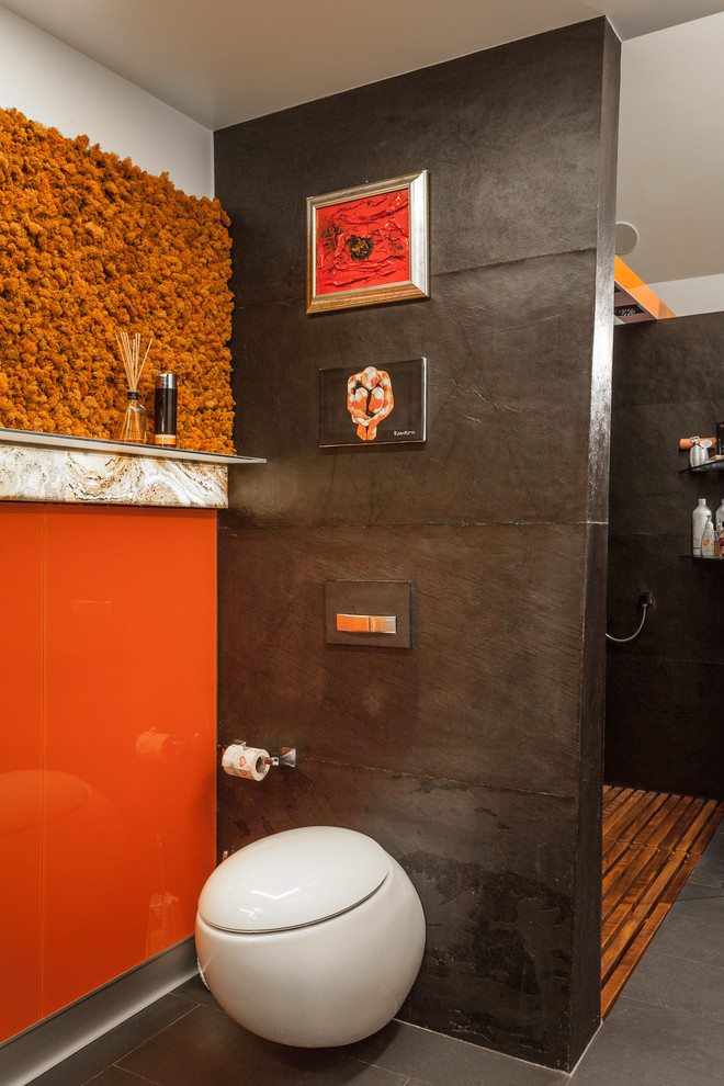 Inredning av ett industriellt mellanstort badrum med dusch, med en vägghängd toalettstol, orange kakel, glaskakel, svarta väggar, klinkergolv i porslin, svart golv, med dusch som är öppen, släta luckor och en öppen dusch