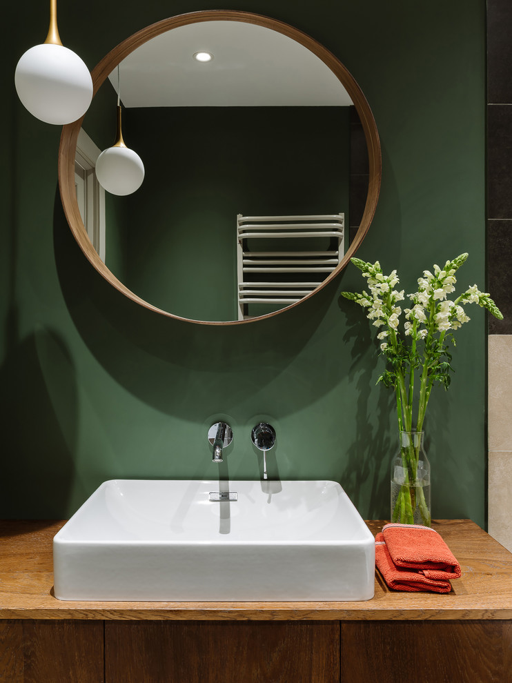 Идея дизайна: маленькая главная ванная комната в современном стиле с плоскими фасадами, фасадами цвета дерева среднего тона, полновстраиваемой ванной, душем над ванной, инсталляцией, разноцветной плиткой, керамогранитной плиткой, разноцветными стенами, полом из керамогранита, накладной раковиной, столешницей из дерева, разноцветным полом, шторкой для ванной и коричневой столешницей для на участке и в саду