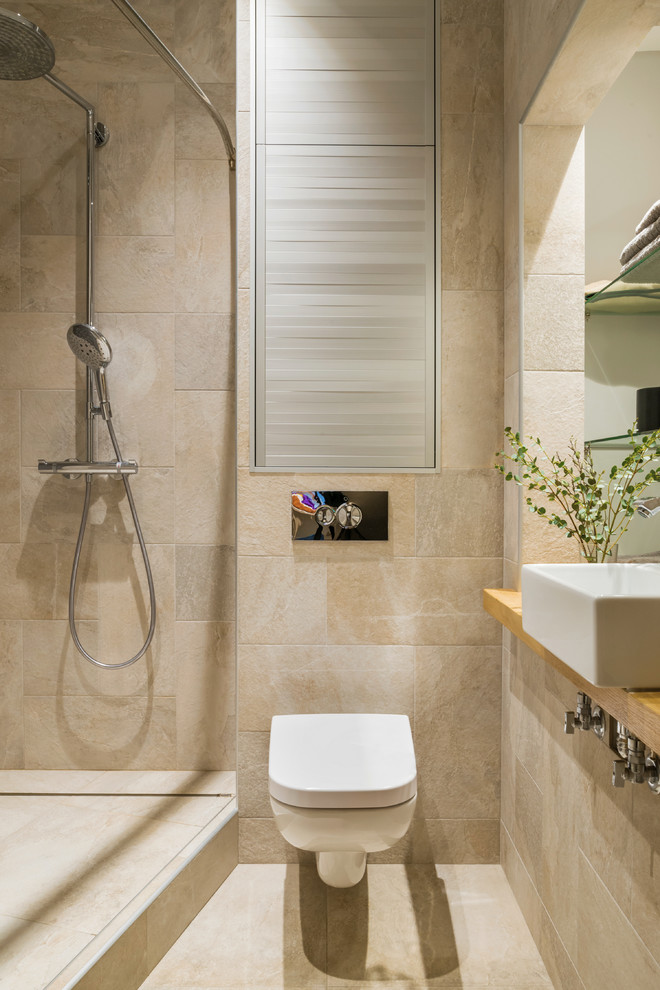 Réalisation d'une salle d'eau design avec WC suspendus, un carrelage beige, une vasque, un sol beige, un plan de toilette en bois et un mur beige.