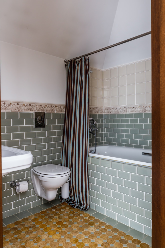 На фото: главная ванная комната в средиземноморском стиле с ванной в нише, душем над ванной, инсталляцией, зеленой плиткой, плиткой кабанчик, белыми стенами, подвесной раковиной, желтым полом и шторкой для ванной с