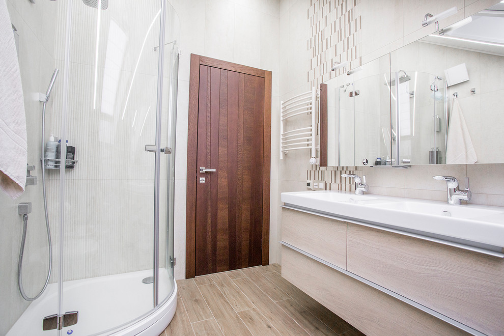 Источник вдохновения для домашнего уюта: ванная комната в современном стиле с плоскими фасадами, светлыми деревянными фасадами, угловым душем, бежевой плиткой, душевой кабиной, раковиной с несколькими смесителями и бежевым полом