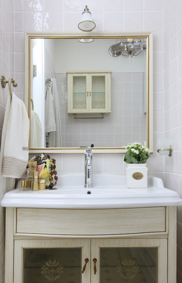 Exemple d'une salle de bain chic en bois clair avec un lavabo intégré, un carrelage blanc et un mur blanc.