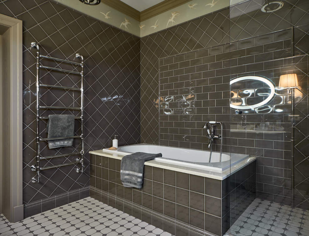Immagine di una stanza da bagno tradizionale con vasca da incasso e piastrelle grigie