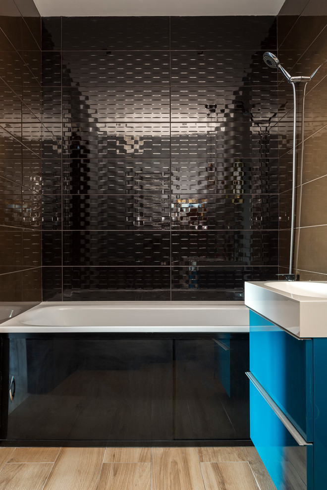 Aménagement d'une salle de bain principale contemporaine avec un placard à porte plane, des portes de placard bleues, une baignoire en alcôve, un combiné douche/baignoire, un carrelage noir et un sol beige.