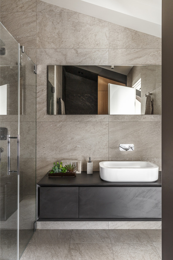 Foto di una stanza da bagno con doccia minimal con ante lisce, ante nere, piastrelle beige, lavabo a bacinella, pavimento beige e top nero