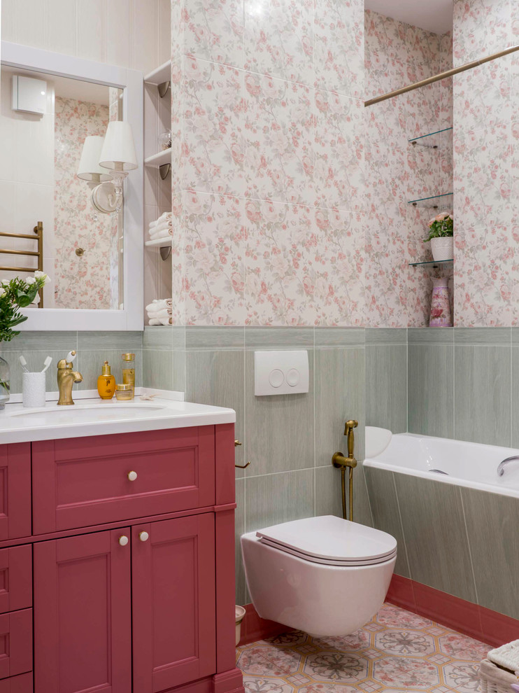 Klassisk inredning av ett mellanstort vit vitt badrum för barn, med luckor med upphöjd panel, röda skåp, ett undermonterat badkar, en vägghängd toalettstol, flerfärgad kakel, keramikplattor, flerfärgade väggar, klinkergolv i keramik, ett undermonterad handfat, bänkskiva i akrylsten och flerfärgat golv