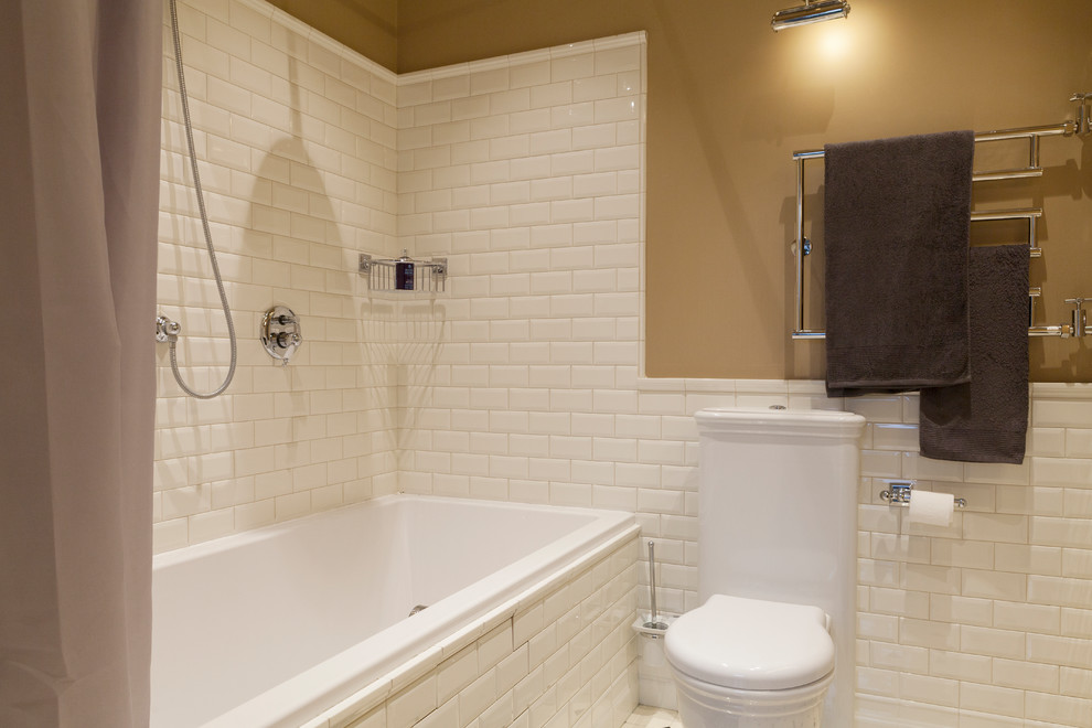 Klassisk inredning av ett en-suite badrum, med en toalettstol med hel cisternkåpa, vit kakel, tunnelbanekakel och beige väggar