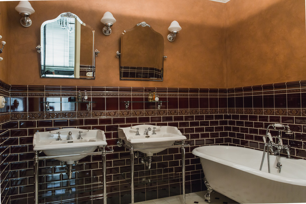 На фото: главная ванная комната в классическом стиле с ванной на ножках, коричневой плиткой, плиткой кабанчик, коричневыми стенами и консольной раковиной с