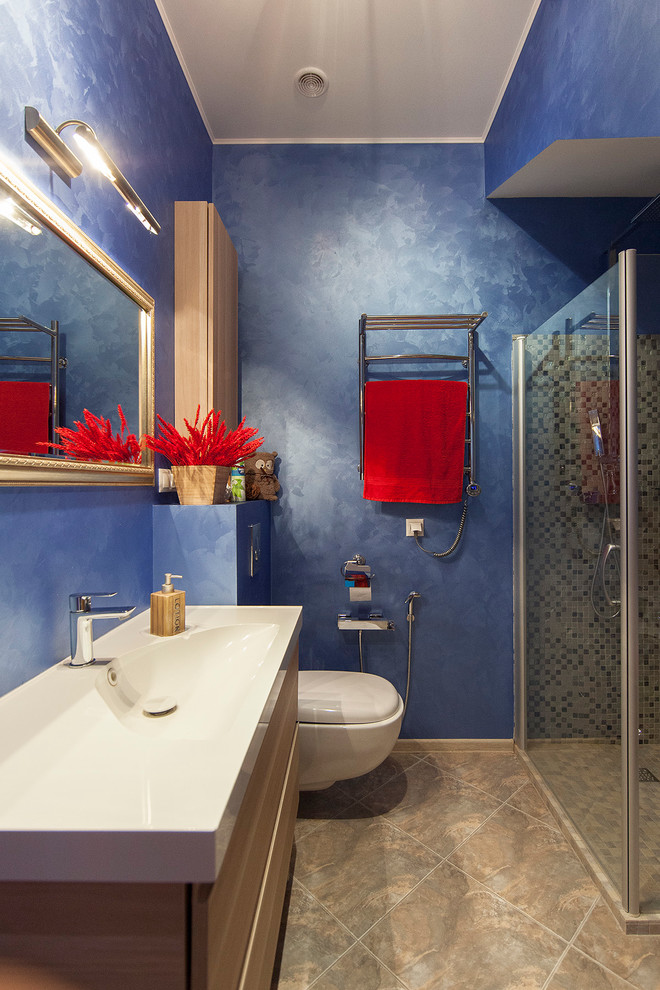 Diseño de cuarto de baño contemporáneo con armarios con paneles lisos, puertas de armario de madera oscura, ducha esquinera, sanitario de pared, paredes azules, aseo y ducha y lavabo integrado