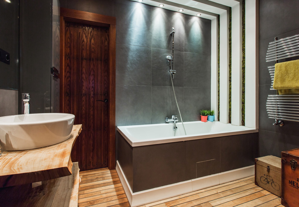 Inspiration för ett funkis en-suite badrum, med öppna hyllor, en dusch/badkar-kombination, grå kakel, målat trägolv, ett fristående handfat, brunt golv och träbänkskiva