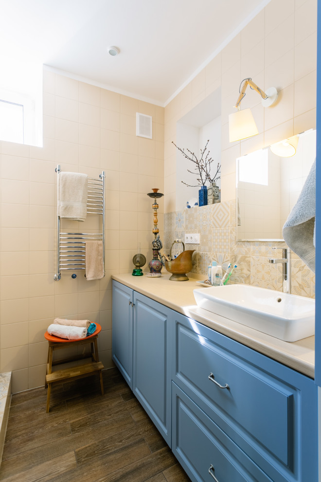 На фото: ванная комната в классическом стиле с фасадами с выступающей филенкой, синими фасадами, бежевой плиткой и настольной раковиной с