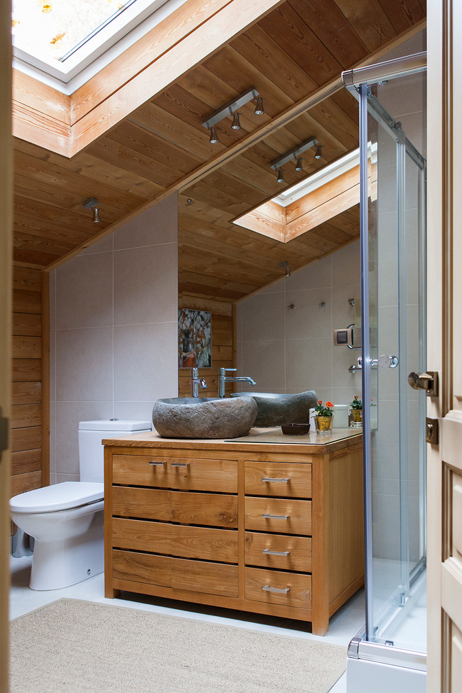 Foto på ett lantligt brun badrum med dusch, med släta luckor, skåp i mellenmörkt trä, en hörndusch, en toalettstol med separat cisternkåpa, vit kakel, bruna väggar, ett fristående handfat, träbänkskiva och dusch med skjutdörr