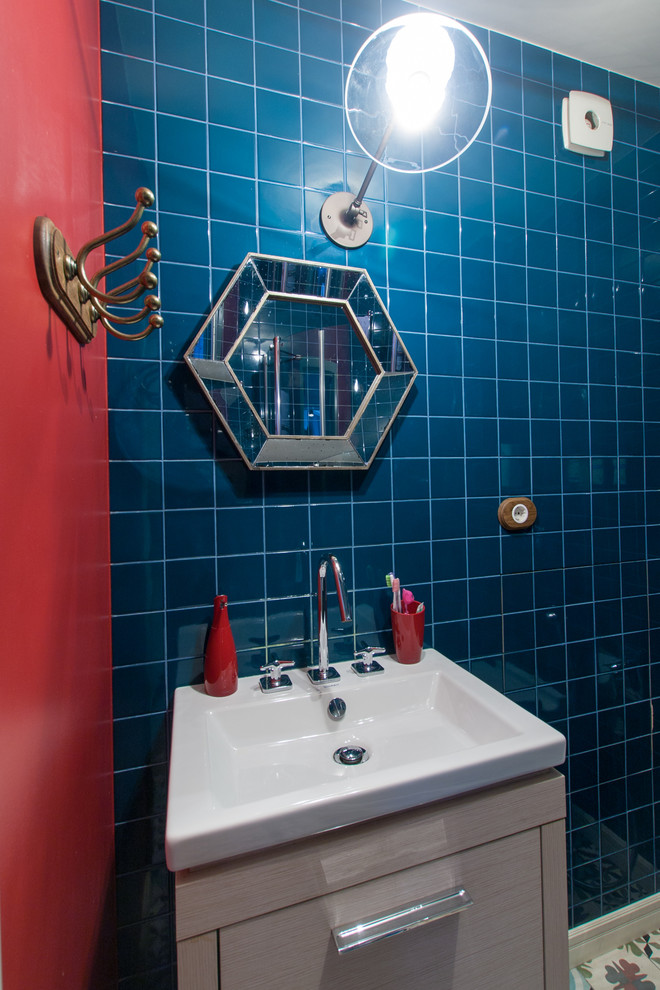 Inredning av ett modernt badrum, med släta luckor, skåp i ljust trä, blå kakel, röda väggar och ett nedsänkt handfat