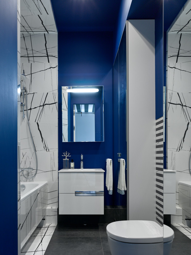 Идея дизайна: ванная комната среднего размера в современном стиле с плоскими фасадами, белыми фасадами, ванной в нише, душем над ванной, инсталляцией, черно-белой плиткой, синими стенами, полом из керамогранита, врезной раковиной, черным полом, открытым душем и белой столешницей