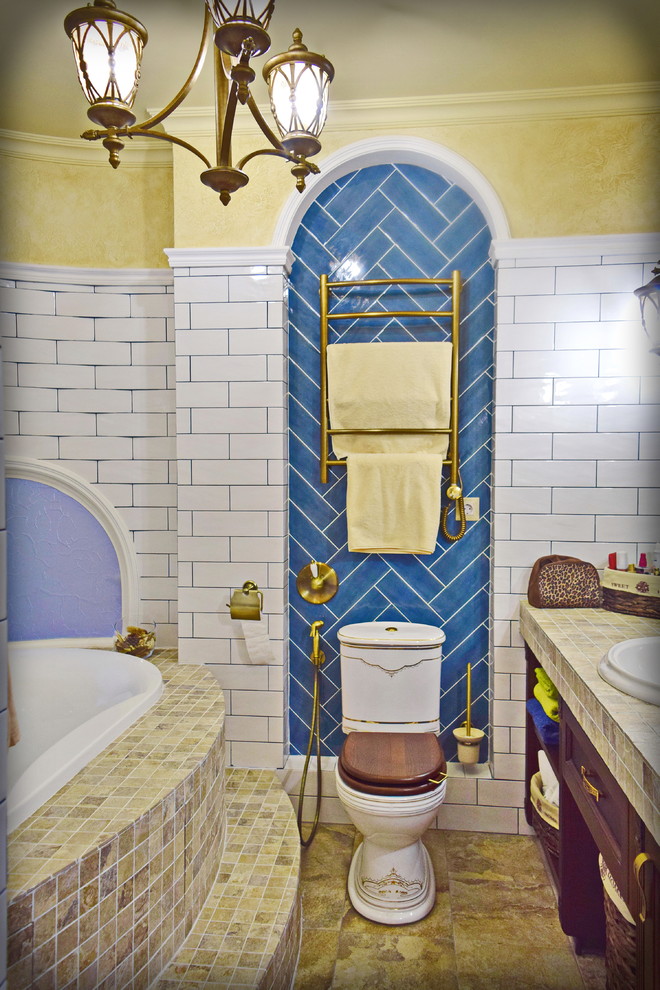 На фото: большая главная ванная комната в стиле неоклассика (современная классика) с фасадами с выступающей филенкой, коричневыми фасадами, накладной ванной, белой плиткой, керамической плиткой, бежевыми стенами, полом из керамогранита, врезной раковиной, столешницей из плитки, бежевым полом, разноцветной столешницей и гигиеническим душем с
