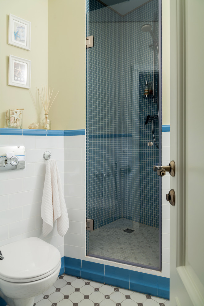 Immagine di una piccola stanza da bagno contemporanea con doccia alcova, WC sospeso, piastrelle blu, piastrelle bianche, pareti beige e pavimento con piastrelle in ceramica