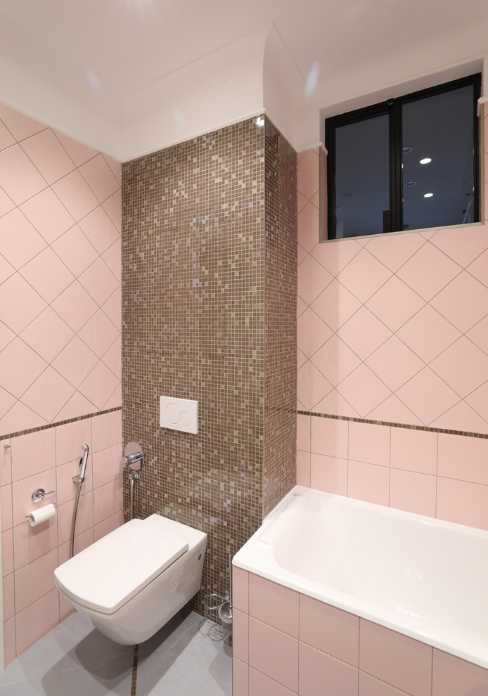 На фото: главная ванная комната среднего размера с плоскими фасадами, белыми фасадами, ванной в нише, угловым душем, инсталляцией, розовой плиткой, керамической плиткой, розовыми стенами, полом из керамической плитки, накладной раковиной, серым полом и душем с раздвижными дверями