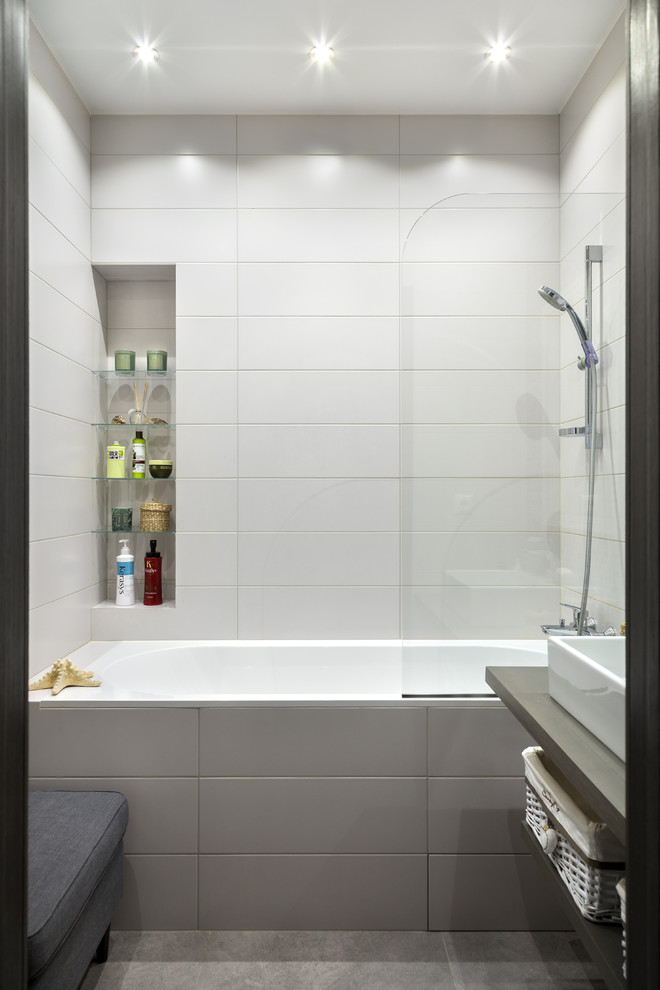 Пример оригинального дизайна: главная ванная комната среднего размера в современном стиле с открытыми фасадами, ванной в нише, белой плиткой, плиткой из известняка, полом из керамической плитки, столешницей из дерева, серым полом, душем над ванной, настольной раковиной и серой столешницей
