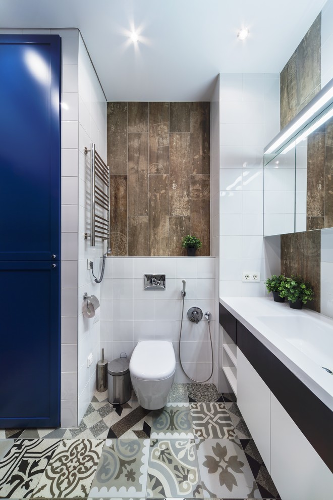 Inspiration för mellanstora moderna en-suite badrum, med en vägghängd toalettstol, vit kakel, brun kakel, blå skåp, ett badkar i en alkov, porslinskakel, vita väggar, klinkergolv i porslin, ett undermonterad handfat, bänkskiva i akrylsten, grått golv, dusch med duschdraperi och släta luckor