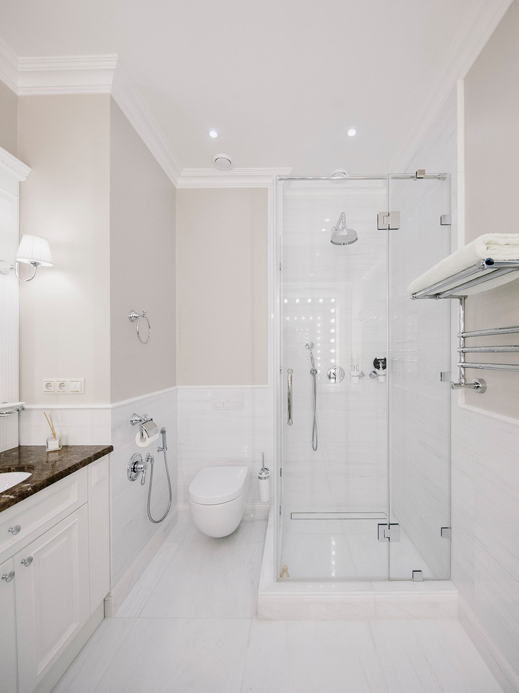 This is an example of a large classic shower room bathroom in Moscow with white cabinets, a corner shower, a wall mounted toilet, white tiles, beige walls, a submerged sink, marble worktops, white floors, a hinged door and brown worktops.