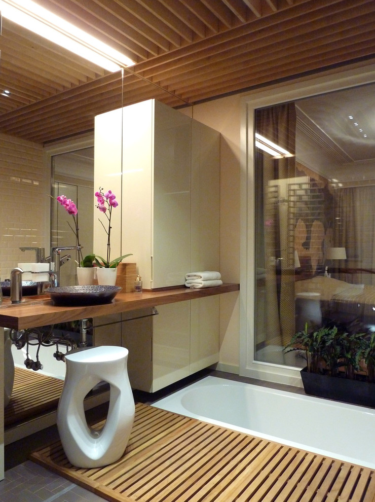 На фото: ванная комната в восточном стиле с бежевой плиткой, керамической плиткой, бежевыми стенами, полом из цементной плитки, столешницей из дерева и настольной раковиной с