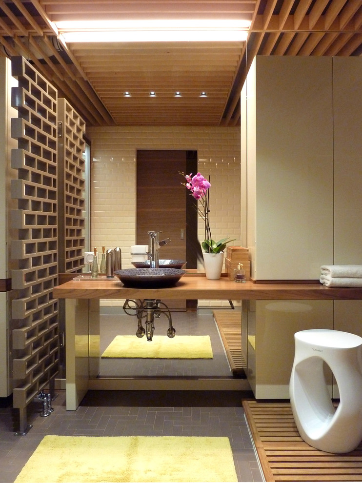 Cette image montre une salle de bain design avec un carrelage beige, des carreaux de céramique, carreaux de ciment au sol, un lavabo posé et un plan de toilette en bois.